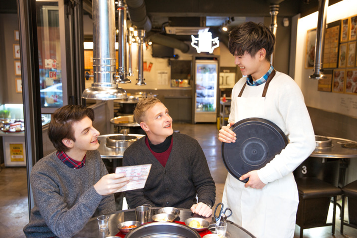 韓國餐廳內部用餐場景的圖片，展示顧客與服務生互動的用餐體驗。