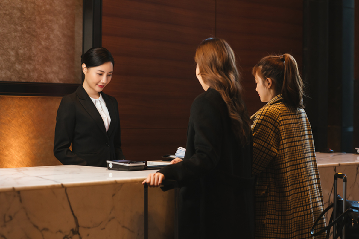 酒店前台的圖片，展示顧客在韓國酒店辦理入住登記的情境。