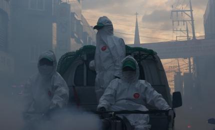 コロナ19の集団感染の予防策として、防護服を着た作業員が環境消毒を行っているソウル市の風景。煙が立ち込める中、教会のシルエットが背景に広がる。2020年9月24日撮影。