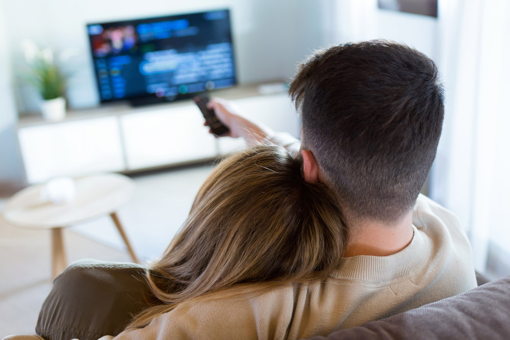 香港家庭影院用迷你投影機放映畫面，蜷縮在沙發上享受戲劇氛圍。