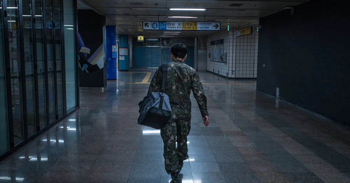 穿著軍服的人物背景在火車站中孤獨行走，呈現軍隊生活的感受。