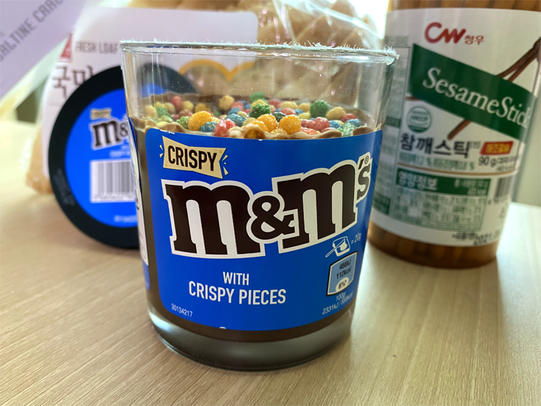 M&M Crispy 초콜릿 스프레드와 참깨 스틱이 함께 있는 테이블의 홍콩 배경 이미지