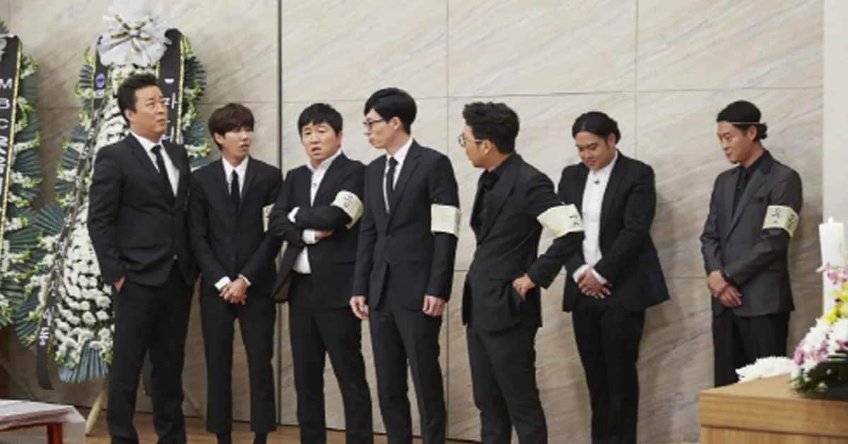 行列站立的韓國喪禮場景，人們身著黑色西裝戴著紗布臂章。
