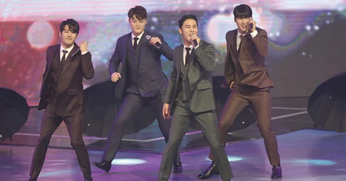 ศิลปินในชุดสูทกำลังทำการแสดงสดบนเวทีในบรรยากาศแบบทางการ