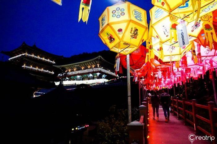 The sun setting over the vibrant lantern display at Samgwangsa Temple, casting a warm glow.