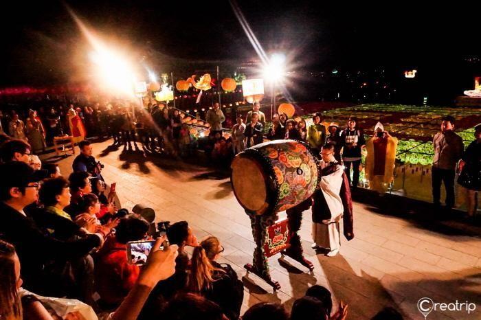 An engaging cultural performance featuring traditional drums and dancers amidst the lantern-lit atmosphere.