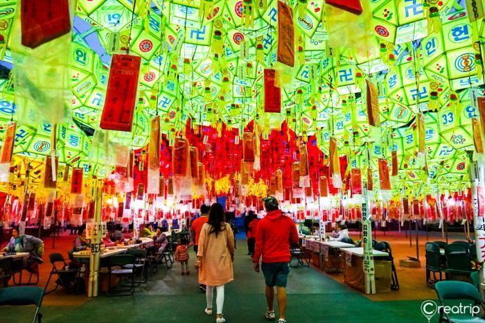 Visitors stroll through a colorful tunnel adorned with vibrant lanterns, filled with wishes at the Busan Lantern Festival.