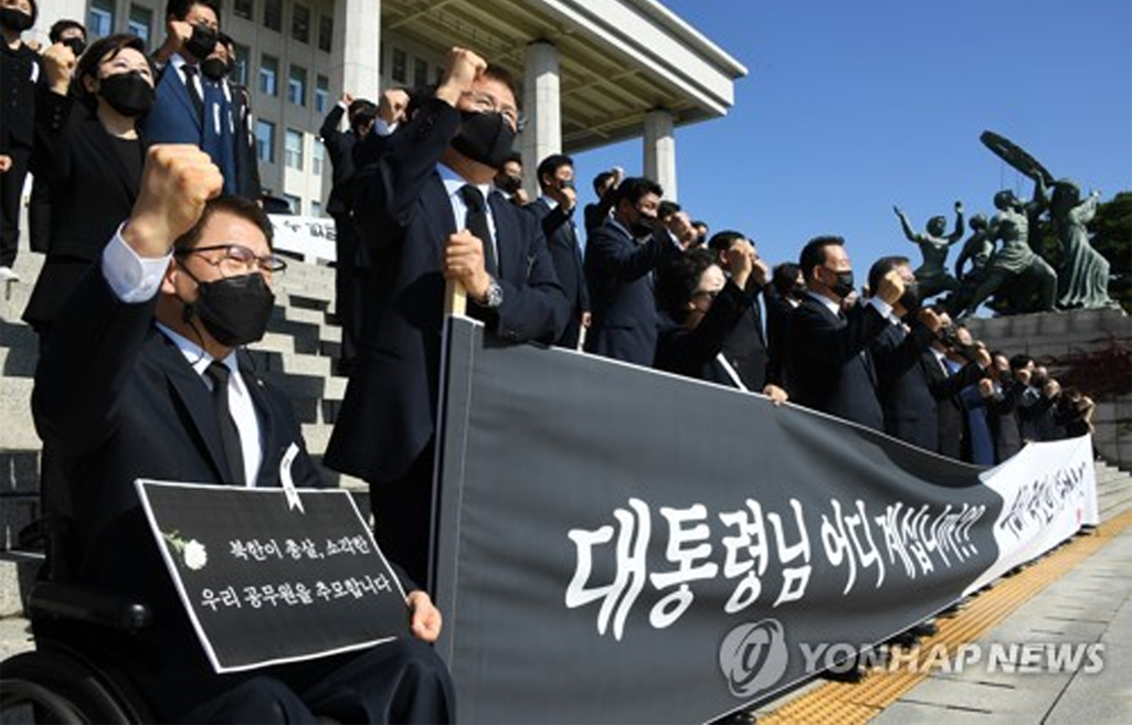 身穿黑色正裝的議員們在國會前臺階上舉起拳頭，背景是展開的橫幅，上面寫著『大統領您在哪裡？』