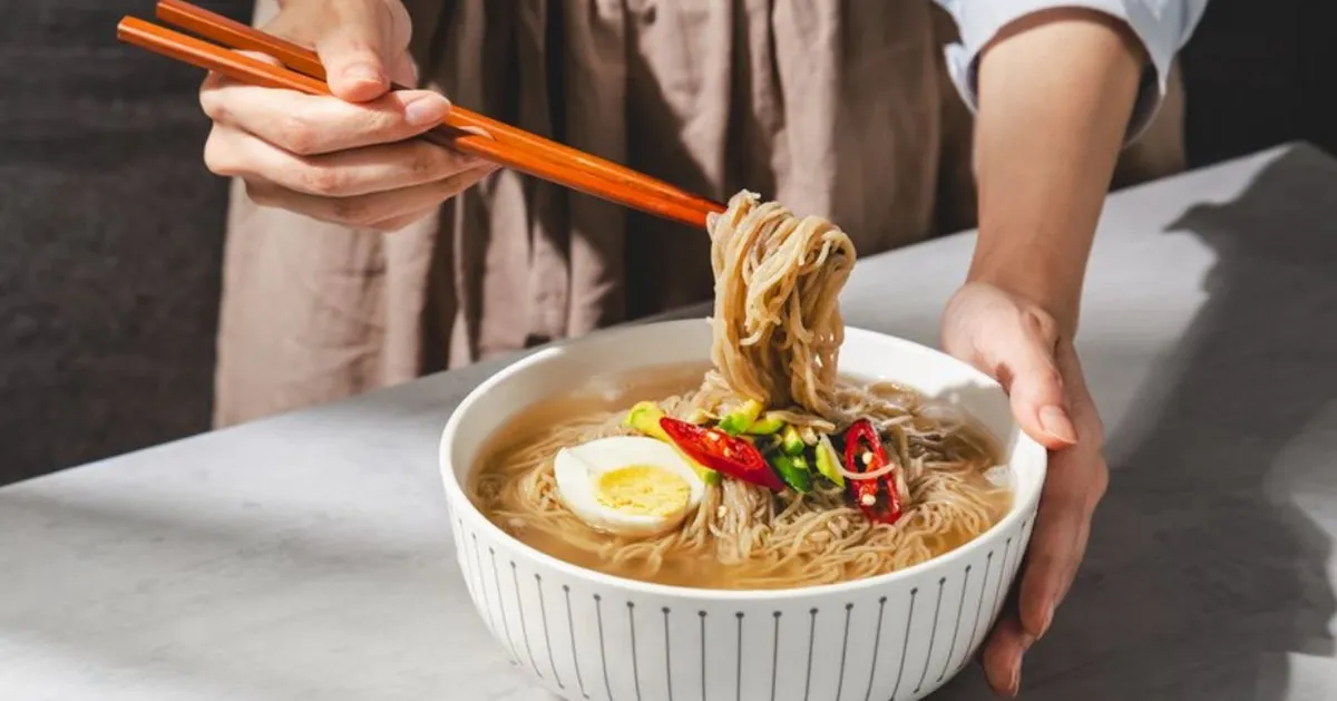 Woman elegantly enjoying a bowl of Korean noodles with chopsticks. 우아하게 한국 면을 즐기는 여성 모습. 대만어에서 국수 추앙.