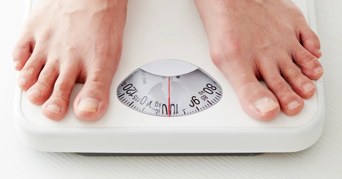 Person standing on a weight scale, symbolizing the high-calorie food theme. 칼로리 표시된 체중계 위에 서 있는 사람의 모습. 대만어에서 체중 증가.