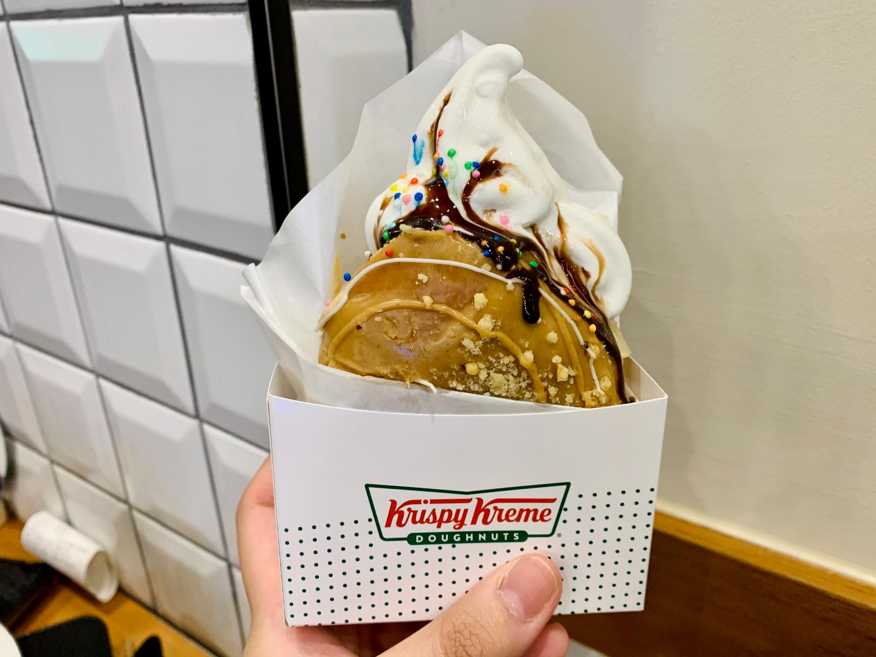 Hand holding the crispy peanut butter donut, topped with a layer of flavorful ice cream. 맛있는 아이스크림을 얹은 크리스피 피넛버터 도넛을 손에 들고 있는 모습. 대만어에서 수박개.