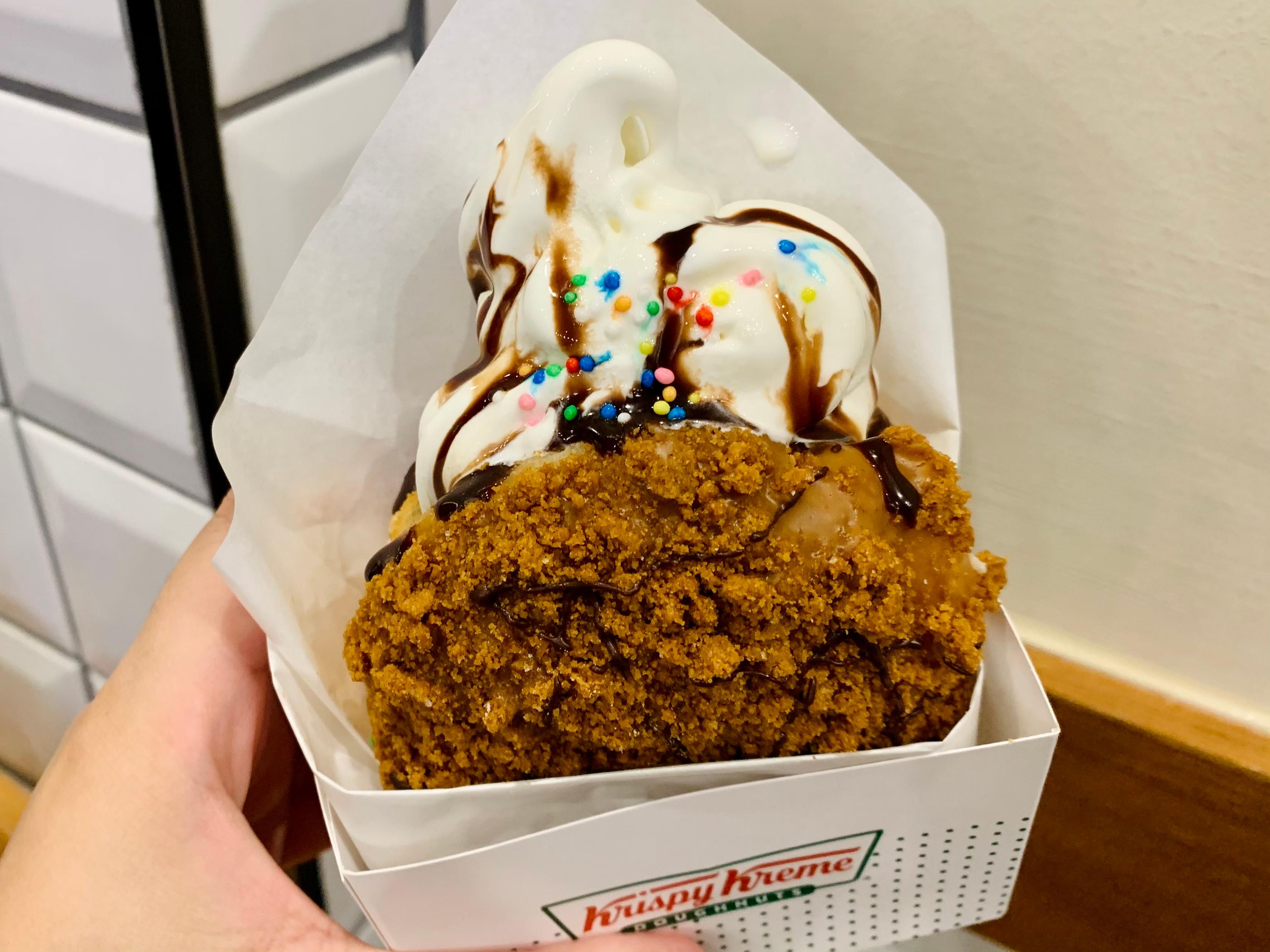 Close-up of the Lotus Biscoff donut from Krispy Kreme with a rich crumb coating and ice cream topping. 크럼핑과 아이스크림으로 장식된 로투스 비스크키프 도넛의 클로즈업. 대만어에서 크럼 푸딩.