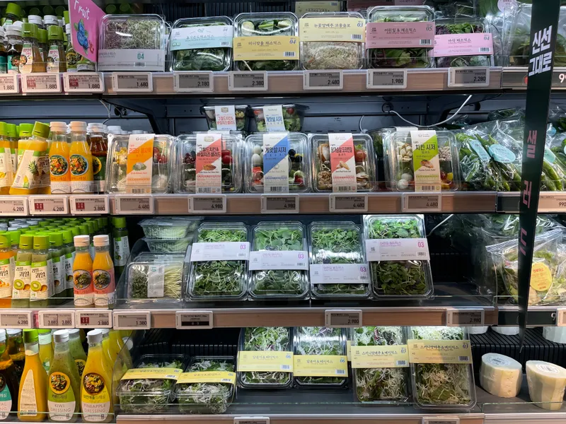 首爾 emart 新村的蔬果區展示了各種包裝的蔬菜，便於單次烹飪，符合年輕消費者的需求。