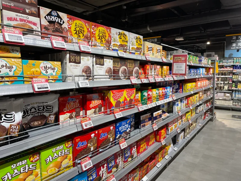 在首爾新村 emart 店內，零食區展示了各種甜食和小吃，吸引顧客的目光。