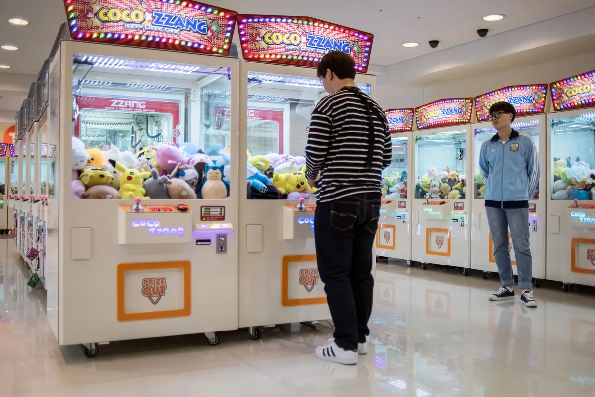 คนกำลังเล่นเกมตู้คีบตุ๊กตาที่ห้างสรรพสินค้าในเกาหลีใต้