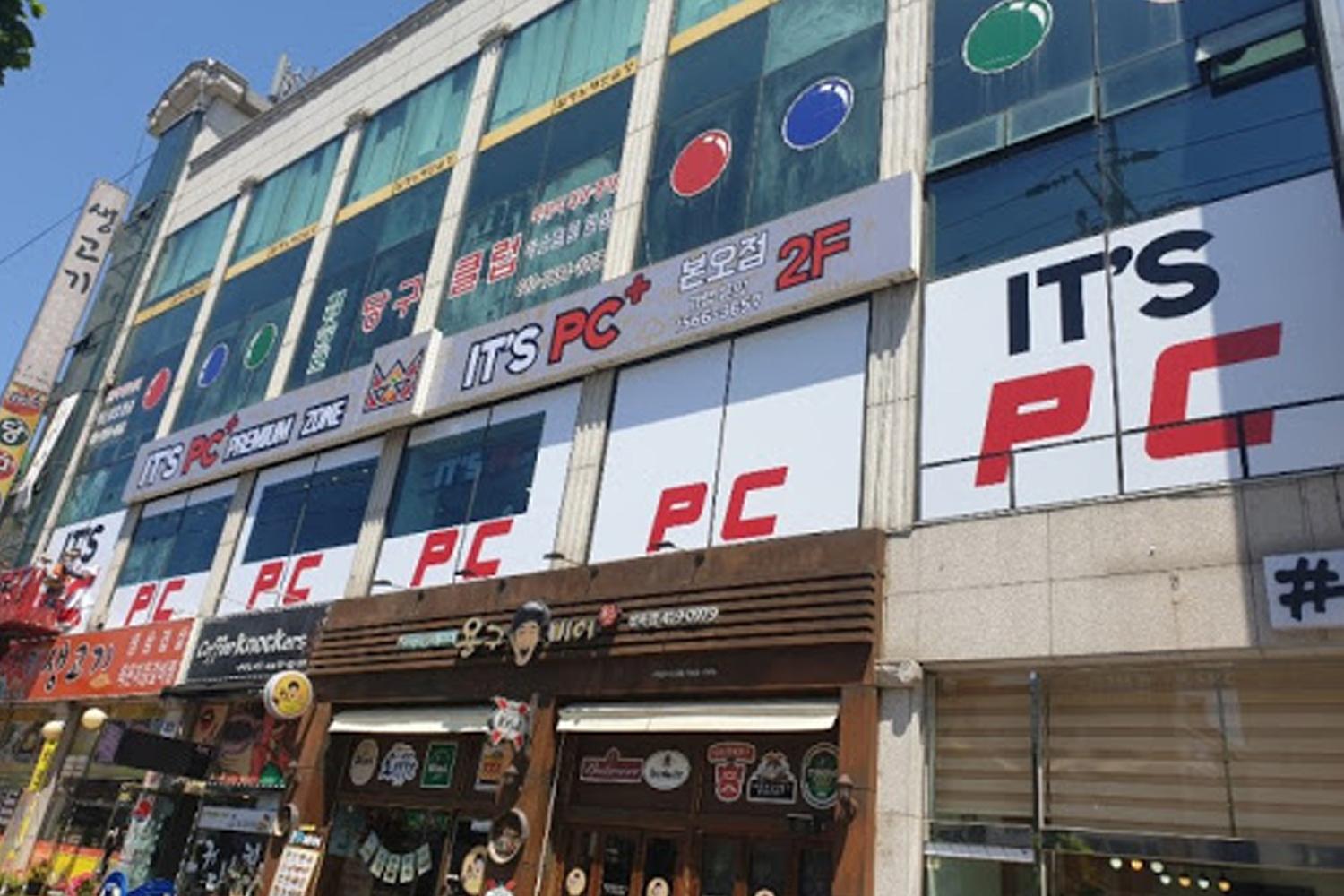 韓國網吧門口及樓外觀，展示多個商店招牌，包括IT'S PC的標誌和位置指示。
