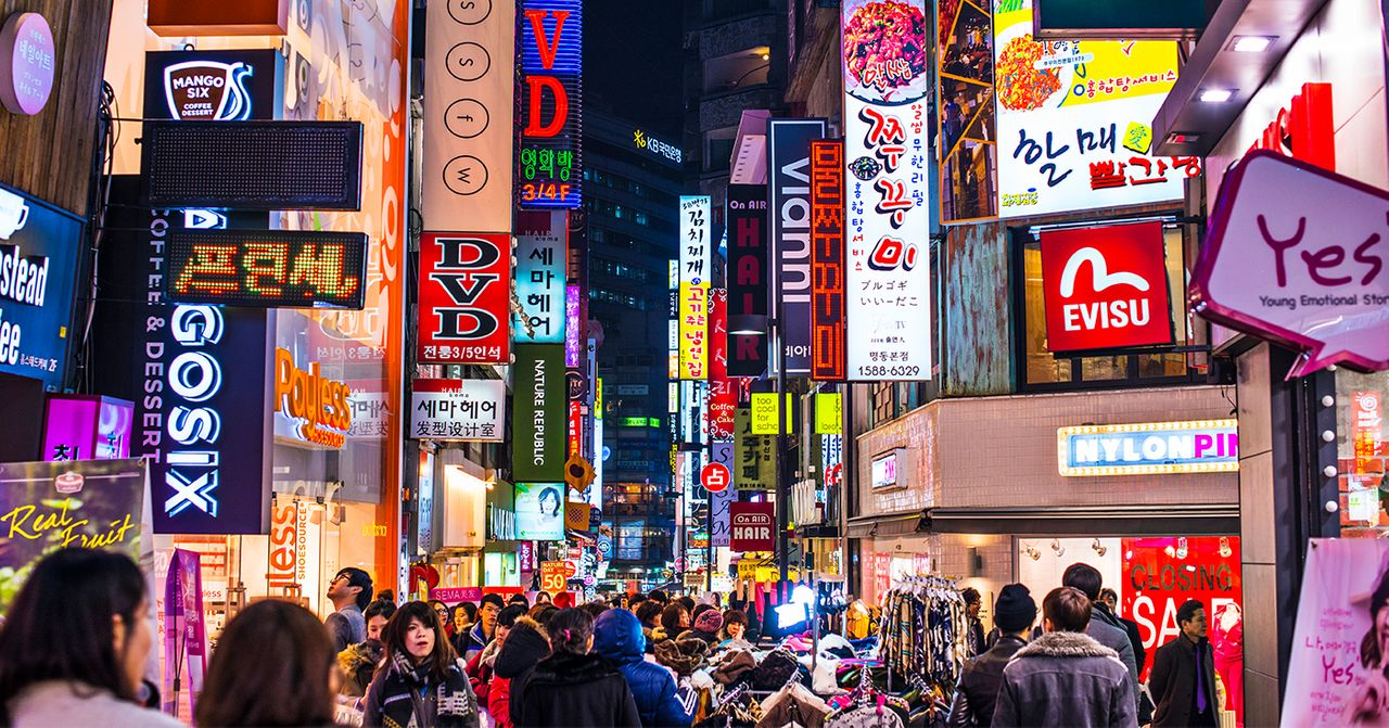 韓國繁忙的夜市街道，亮眼的霓虹招牌吸引著遊客。