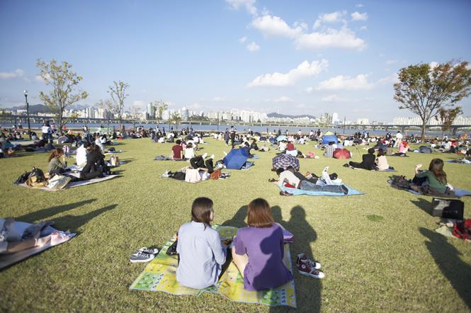 漢江公園的草地上，許多人圍坐在野餐墊上享受午後時光。
