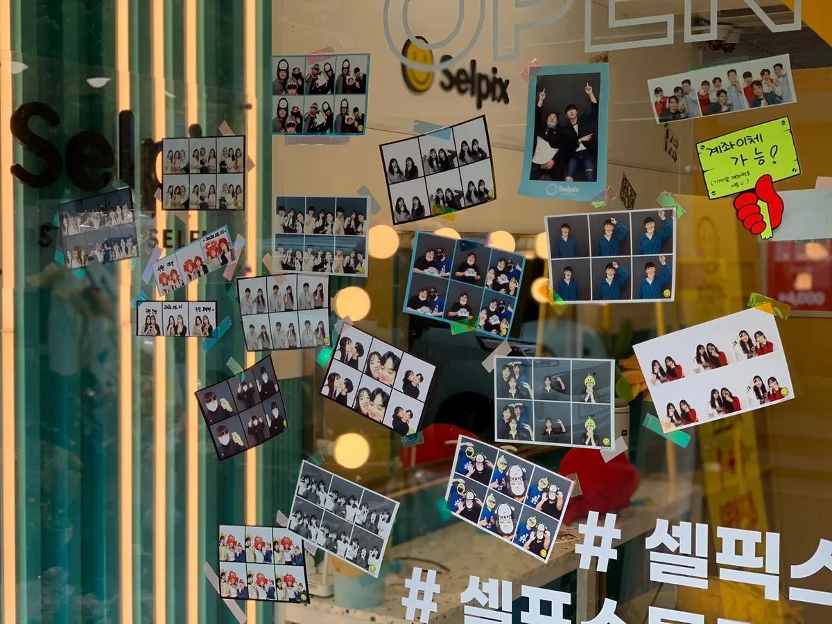韓國拍照館展示窗上貼滿多張拍立得照片，展示當地流行文化。