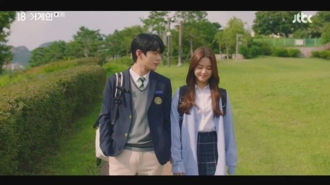 《重返18岁》剧集中的校园场景,身穿校服的年轻男女角色漫步在绿茵小道上,营造出青春浪漫的氛围。