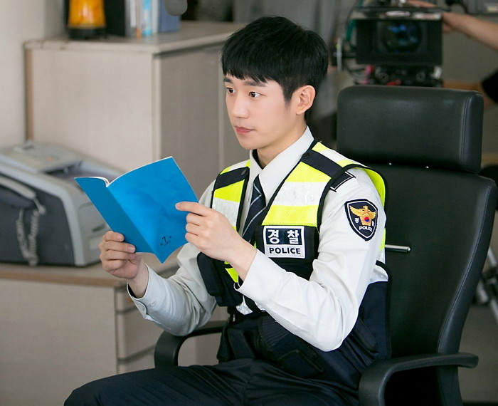 Polizeibeamter in Uniform hält ein blaues Notizbuch, bereit zur Aufnahme am Arbeitsplatz in einem Büro in Südkorea.