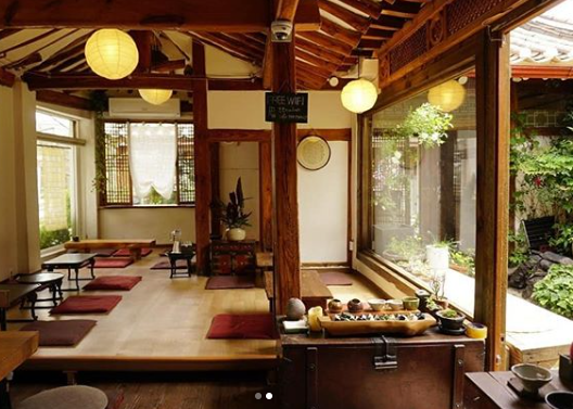 カフェ「뜰안(トゥルアン)」の木造インテリアデザイン。韓国の伝統的な座席スタイルで温かみのある照明が特徴です。