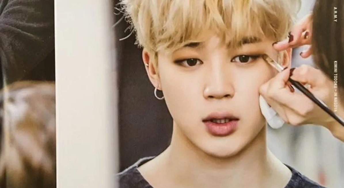 ช่างแต่งหน้ากำลังใช้แปรงแต่งหน้าแต่งผู้หญิงคนหนึ่ง ฉากหลังเป็นห้องแต่งตัว