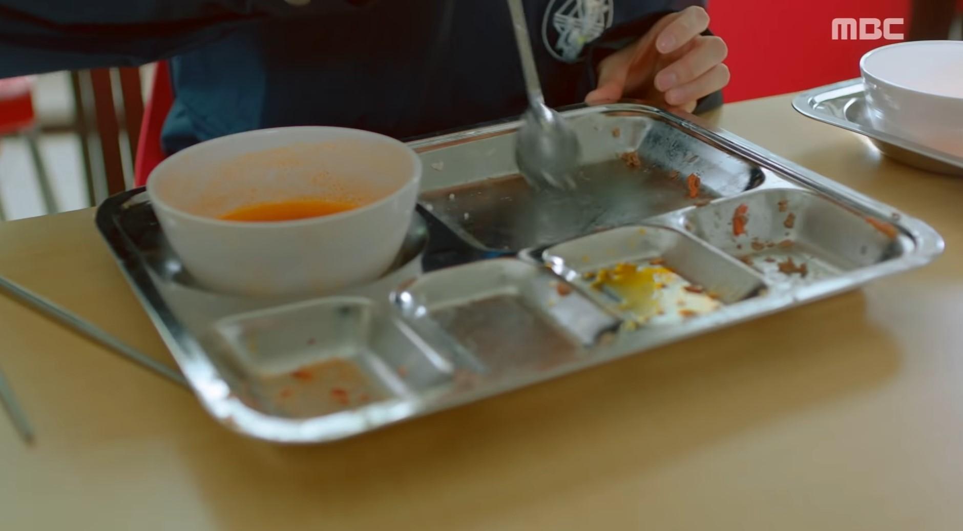 韓国の学生が食堂で使用するスチール製のランチプレートにスープのボウルを乗せ、食事を楽しんでいる様子。