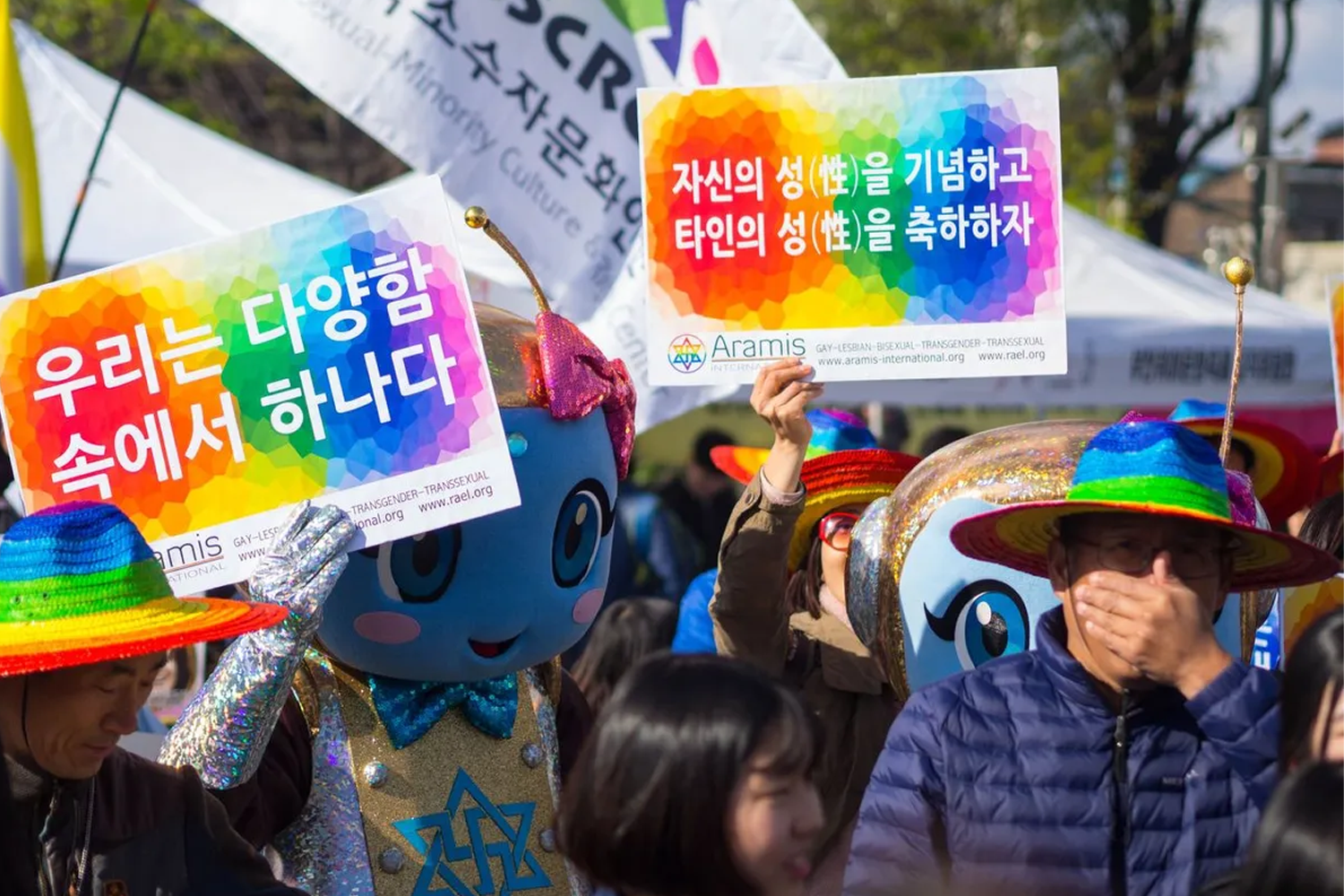 韓國某地的教會建築外觀，白色與橫藍色相間的牆身上寫有韓文名稱，樹枝在畫面右側延伸