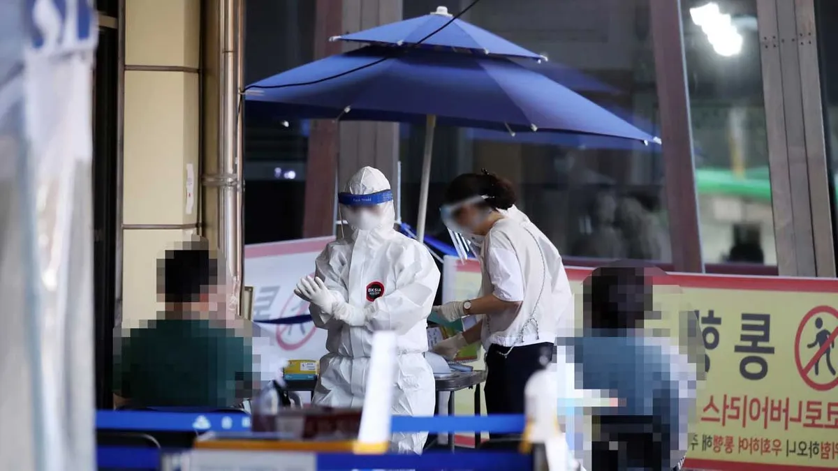 เจ้าหน้าที่สาธารณสุขในชุดป้องกันส่วนบุคคล PPE ดำเนินการคัดกรองโควิด-19 ตามมาตรการความปลอดภัยในเกาหลีใต้