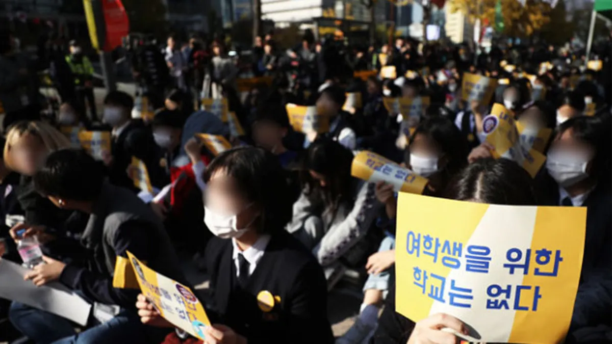 ผู้ชุมนุมถือป้ายประท้วงเกี่ยวกับการศึกษาในเกาหลีในบรรยากาศที่ขมุกขมัวและจริงจัง สะท้อนปัญหาชุดนักเรียนในระบบการศึกษาเกาหลี