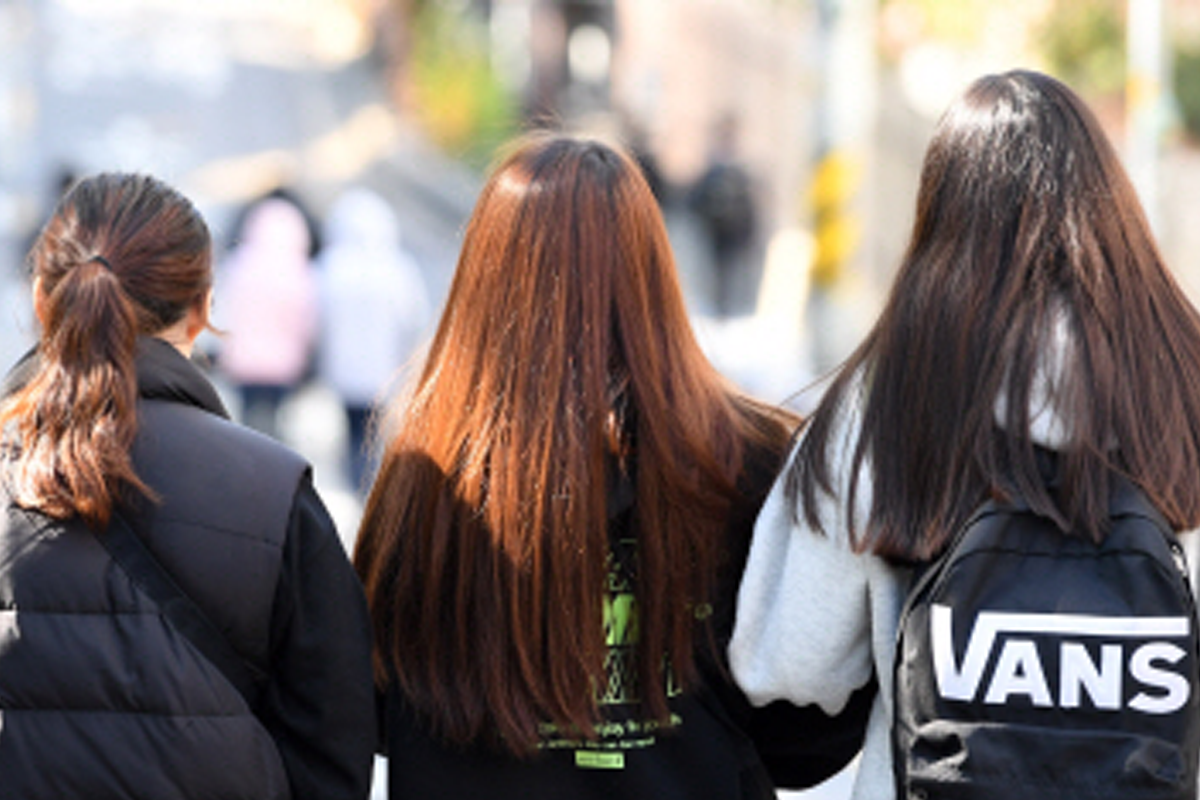 韓國中學生穿著休閒裝，不同髮色的女生們行走於校園，展示自由的校園文化。