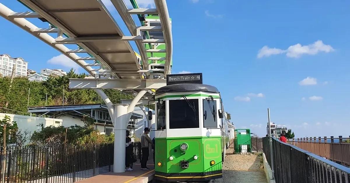 รถไฟสายสีเขียว Haeundae Blue Line พร้อมผู้คนรอโบกี้ที่สถานีแพลตฟอร์มในวันที่อากาศแจ่มใส