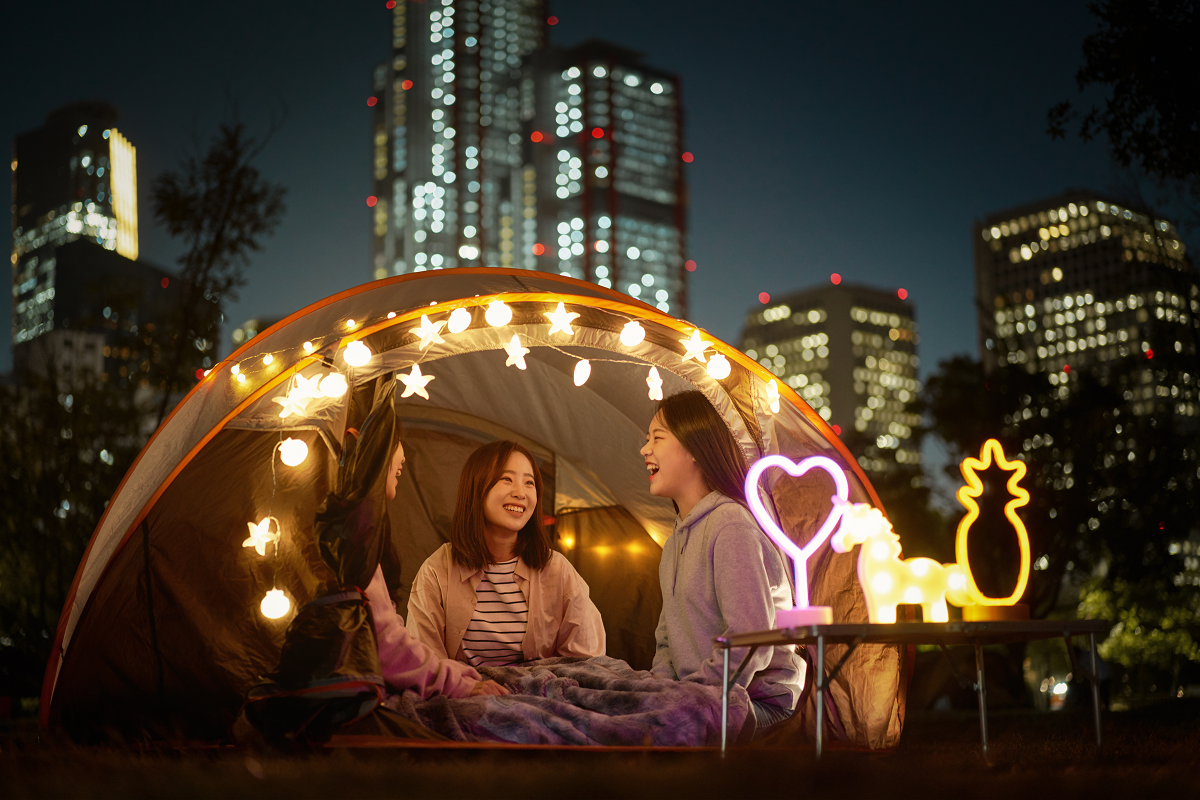 韓国の夜の公園でライトアップされたテントの中で談笑する様子。