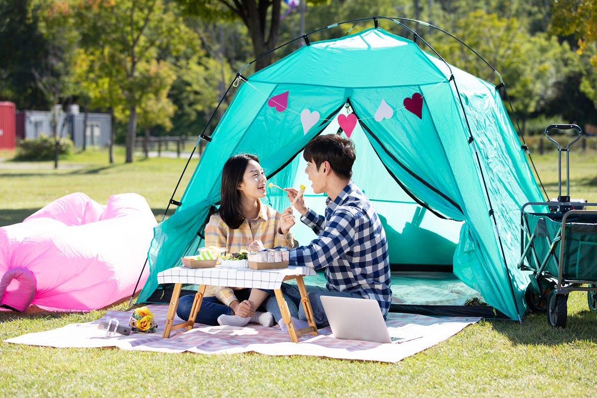 韓国の公園で緑のテントの前でピクニックを楽しむカップル。