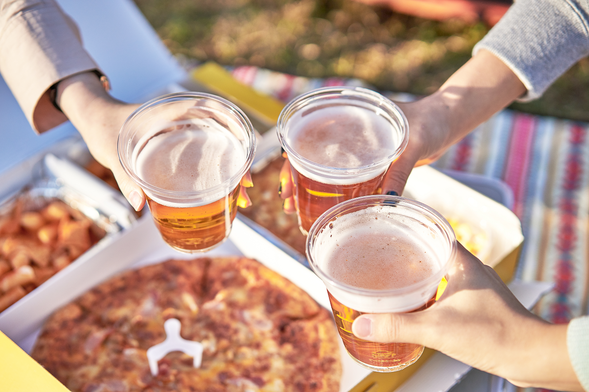 ピザとビールが並べられたピクニックで乾杯をするシーン。