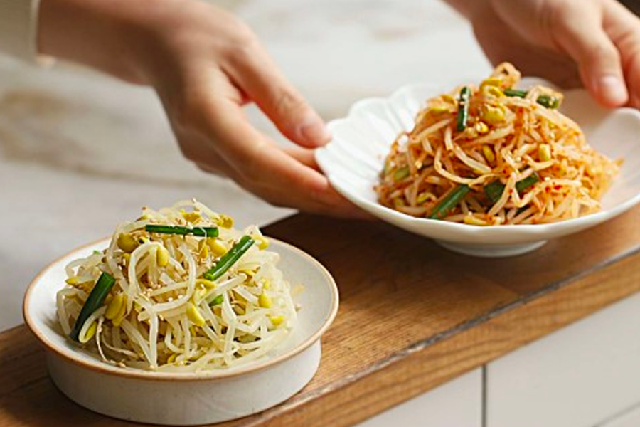 两盘不同味道的凉拌黄豆芽准备端上餐桌