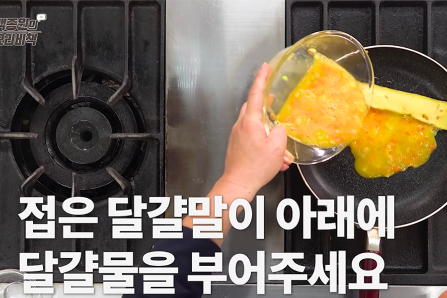 将蛋液倒入锅中，过程展示如何卷起鸡蛋卷