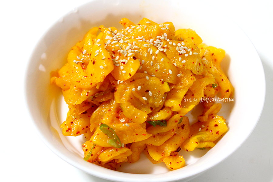 金黄腌萝卜切片，搭配芝麻和辣椒调味料