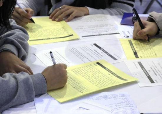 几个人正在认真填写入学申请文件，显示推甄入学的审核程序。