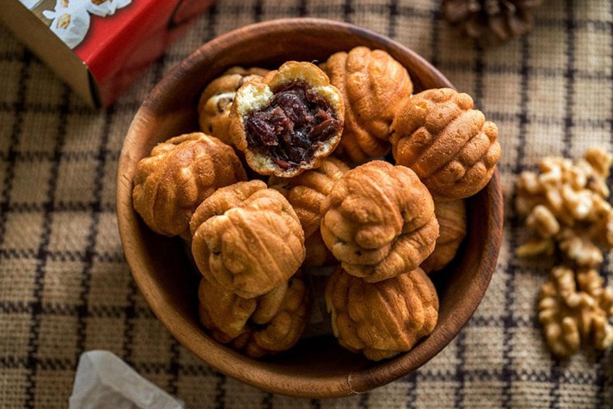 호두과자 이미지는 한국 겨울철 인기 간식으로, 호두와 팥을 채운 고소하고 달콤한 간식입니다. 바삭한 껍질 안에 부드러운 속재료가 들어있는 모습이 돋보입니다.