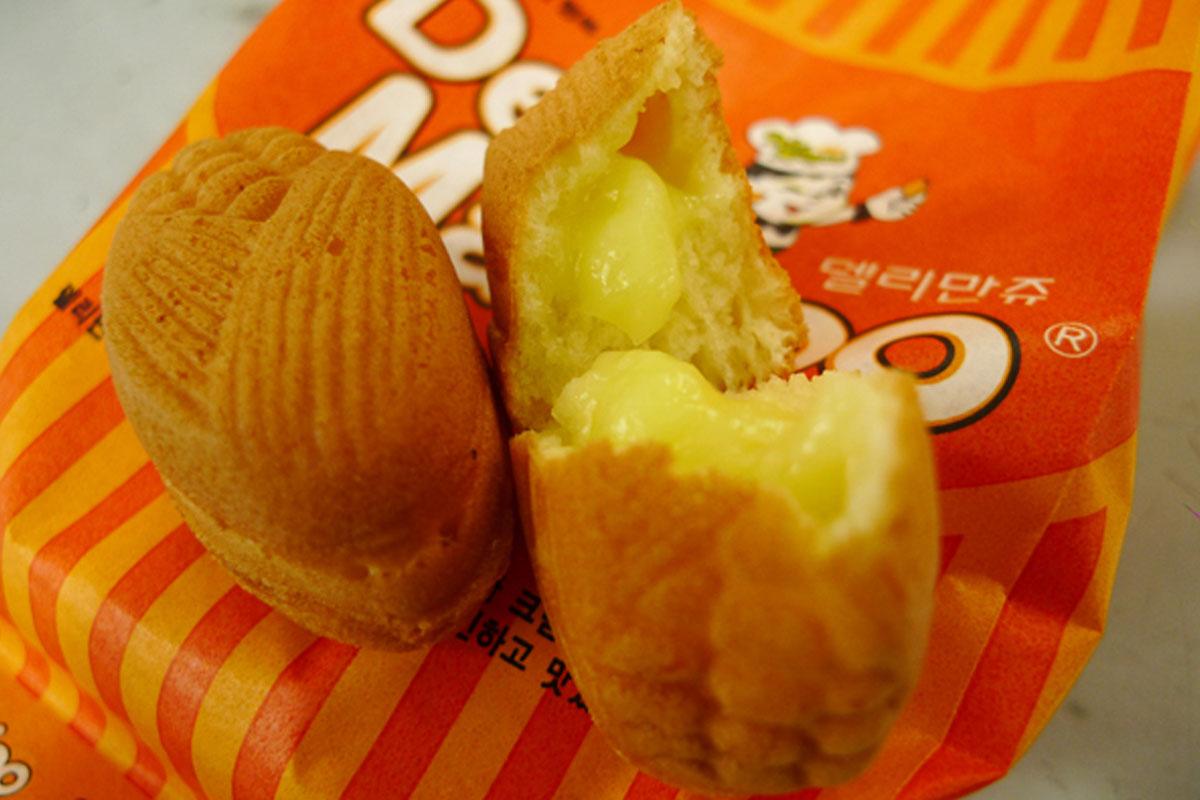 델리만쥬 이미지는 달콤한 커스터드 크림이 가득한 작은 도넛 형태의 디저트로, 부드러운 식감과 함께 손에 꼭 맞는 크기로 한국에서 인기가 많은 간식입니다.