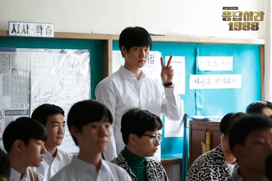 多位韓國高中生坐在教室裡，藍色牆上貼有學生創意作品。