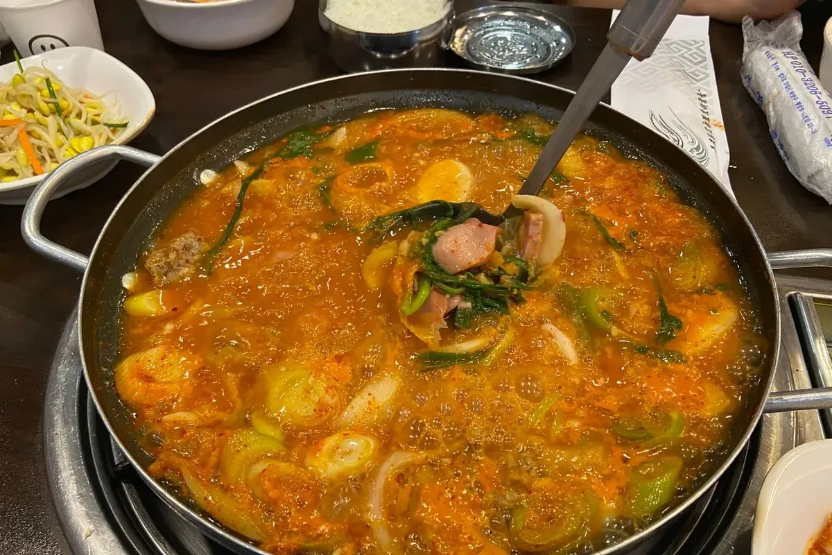 热腾腾的韩国部队锅在餐桌上,即将为食客带来丰富的韩国烹饪体验。