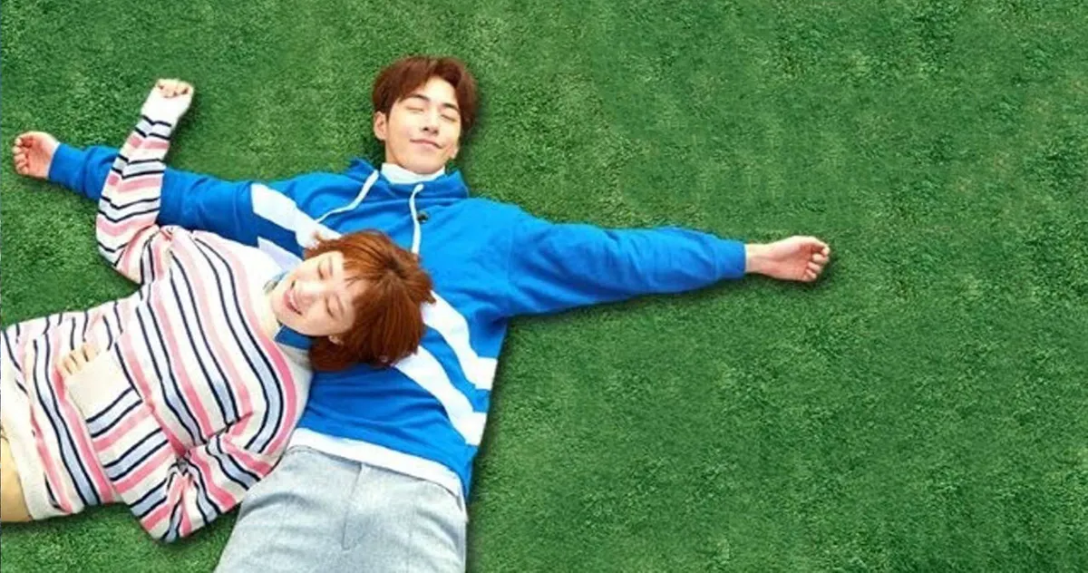 ชายและหญิงนอนเล่นอยู่บนสนามหญ้า สวมใส่เสื้อผ้าธรรมดา แสดงถึงการพักผ่อนในบรรยากาศธรรมชาติในวันที่อากาศดี