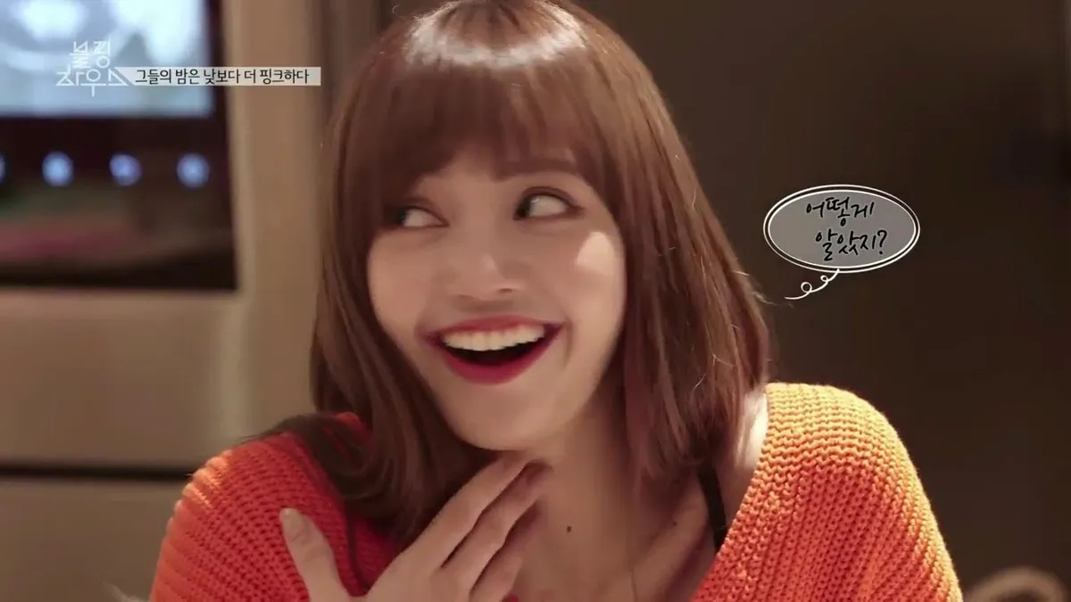 หญิงสาวในสตูดิโอเคเบิลทีวีที่มีคำถามในฟองคำพูดในภาษาเกาหลีบนหน้าจอ