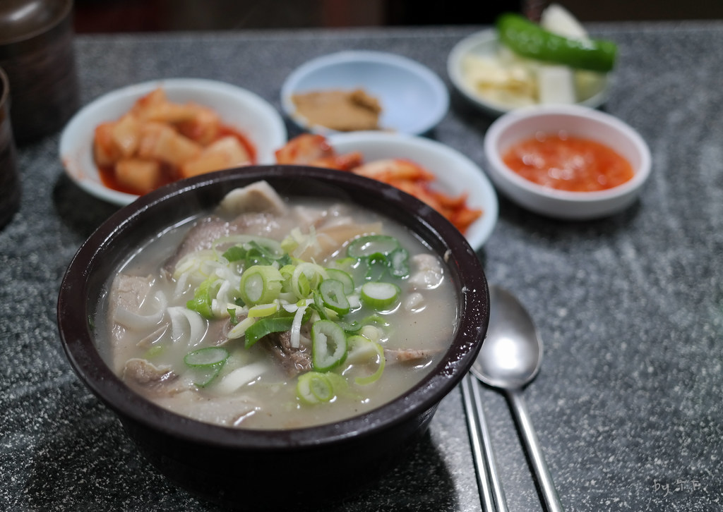 一碗韓國傳統的豬肉湯飯，搭配著泡菜和醬料的小菜，呈現豐富的韓國料理風味。