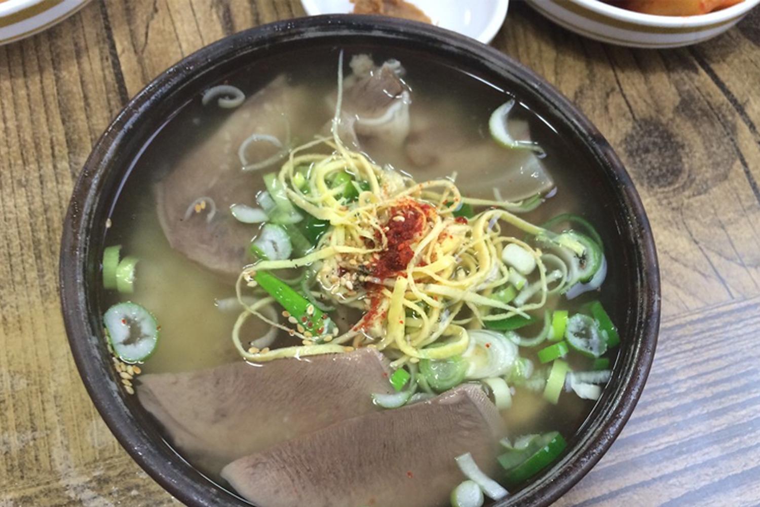 韓國餐館中的牛骨湯，裡面有牛肉片、葱花和紅辣椒的圖片。