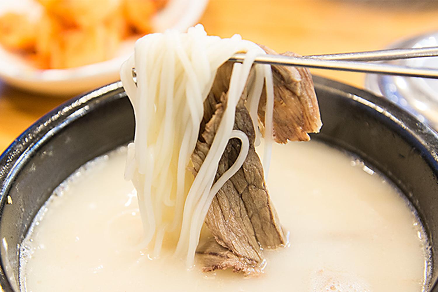 韓國餐館中的一碗牛肉麵湯，突出牛肉塊和幼麵的圖片。
