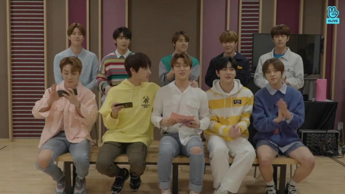 นักร้องเกาหลีในชุดลำลองและเสื้อเชิ้ตสีสันสดใสนั่งบนม้านั่งในห้องสตูดิโอ ภาพแสดงถึงสไตล์ที่ผสมผสานกันระหว่างความสบายและแฟชั่นที่ดูอบอุ่น สะท้อนความนิยมในวัฒนธรรมแฟชั่นเกาหลี